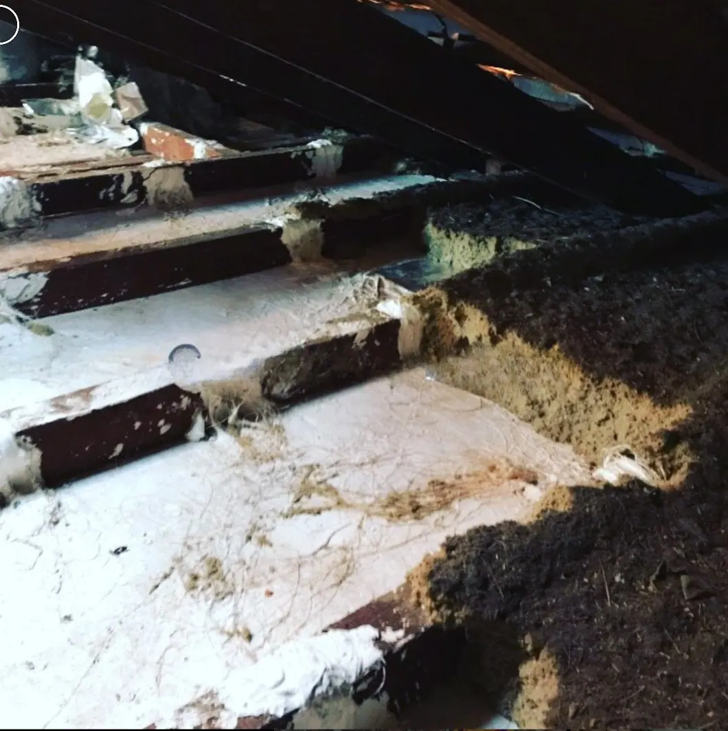 Old ceiling insulation being removed from a roof cavity